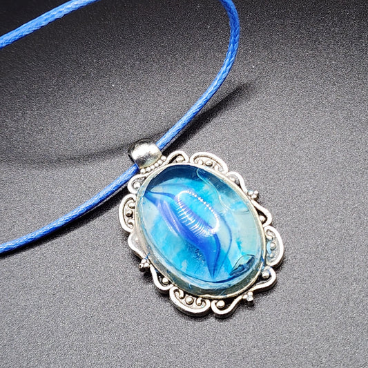 Ocean-inspired blue resin pendant necklace with antique-style silver frame and blue cord.