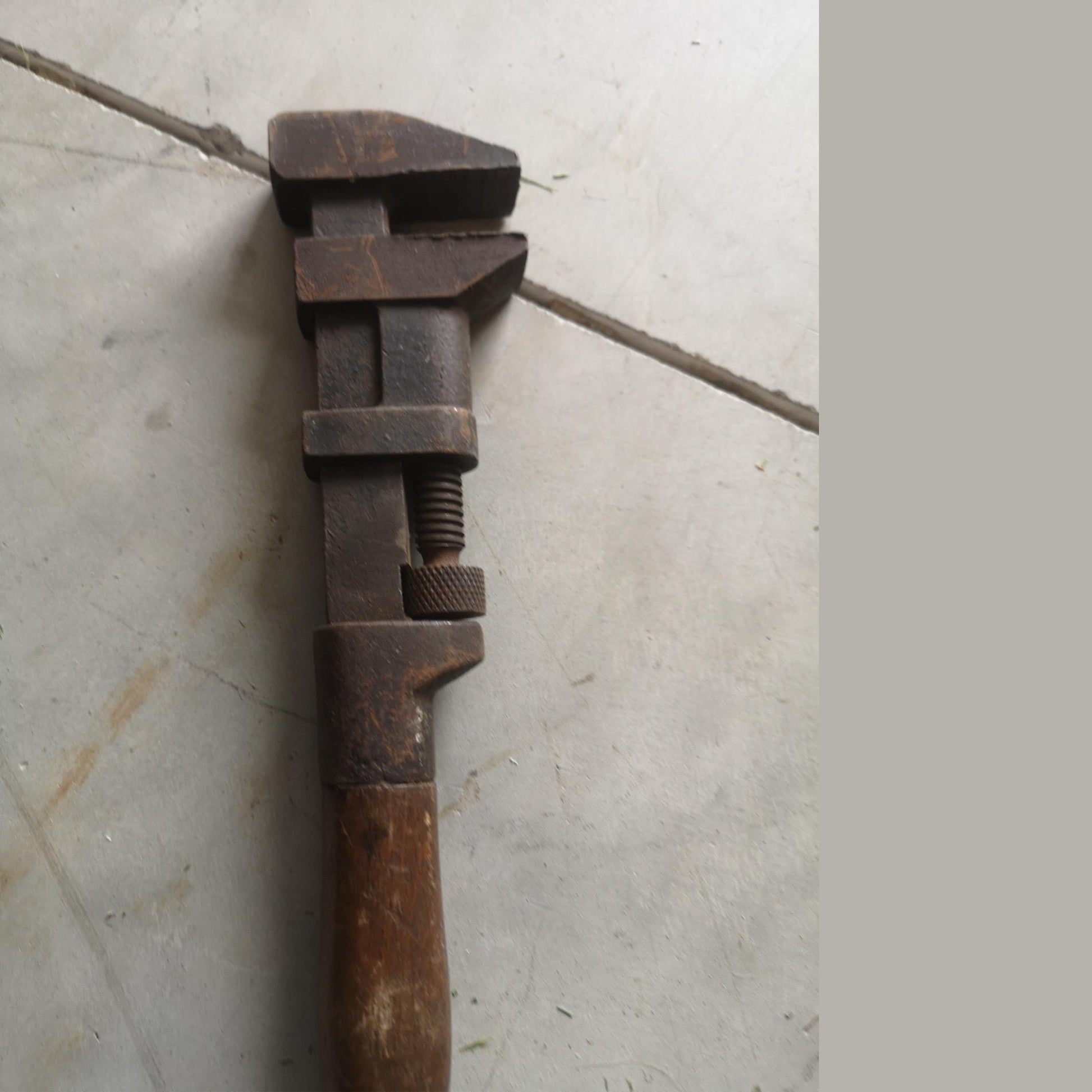 Vintage adjustable pipe wrench with a heavy-duty metal frame, wooden handle, and adjustable jaw showcasing rustic charm