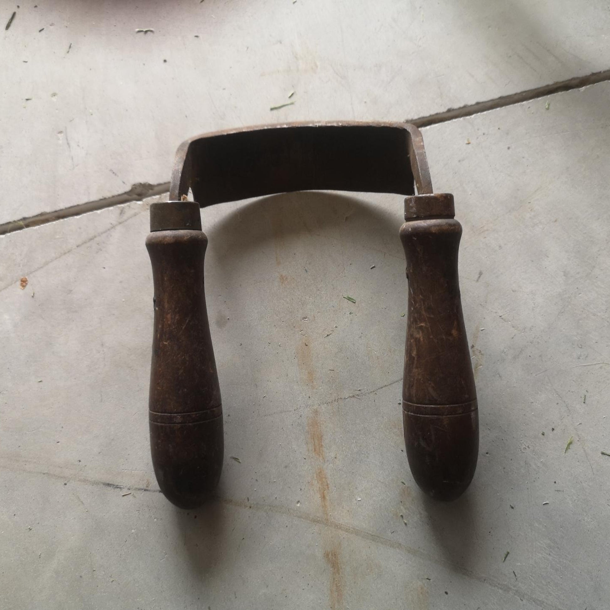 Vintage draw knife with a steel blade and wooden handles, showcasing its historical craftsmanship