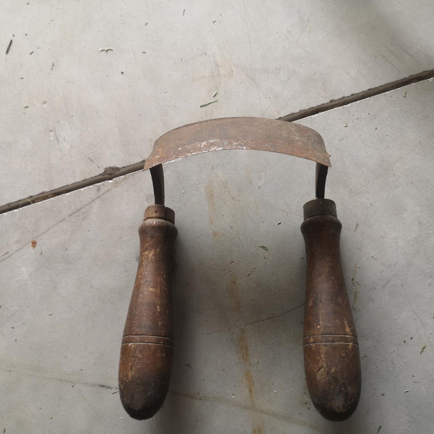 Vintage draw knife with a steel blade and wooden handles, showcasing its historical craftsmanship