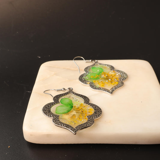 Botanical resin earrings with green and yellow botanicals in clear resin and silver frames 