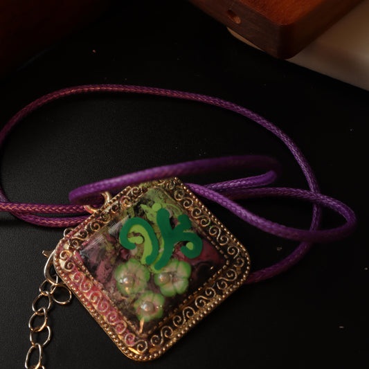 Bohemian Floral and Scrollwork Pendant with Purple Cord, featuring golden accents and whimsical floral design