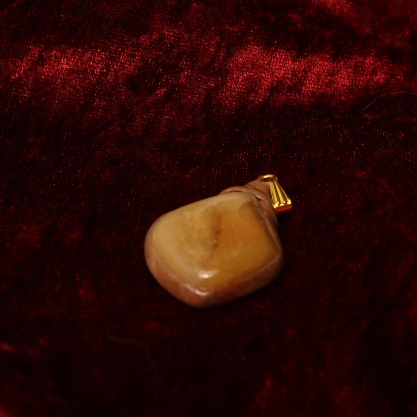 Handcrafted clay pendant with a polished stone, wrapped in earthy tones and finished with a gold-tone bail