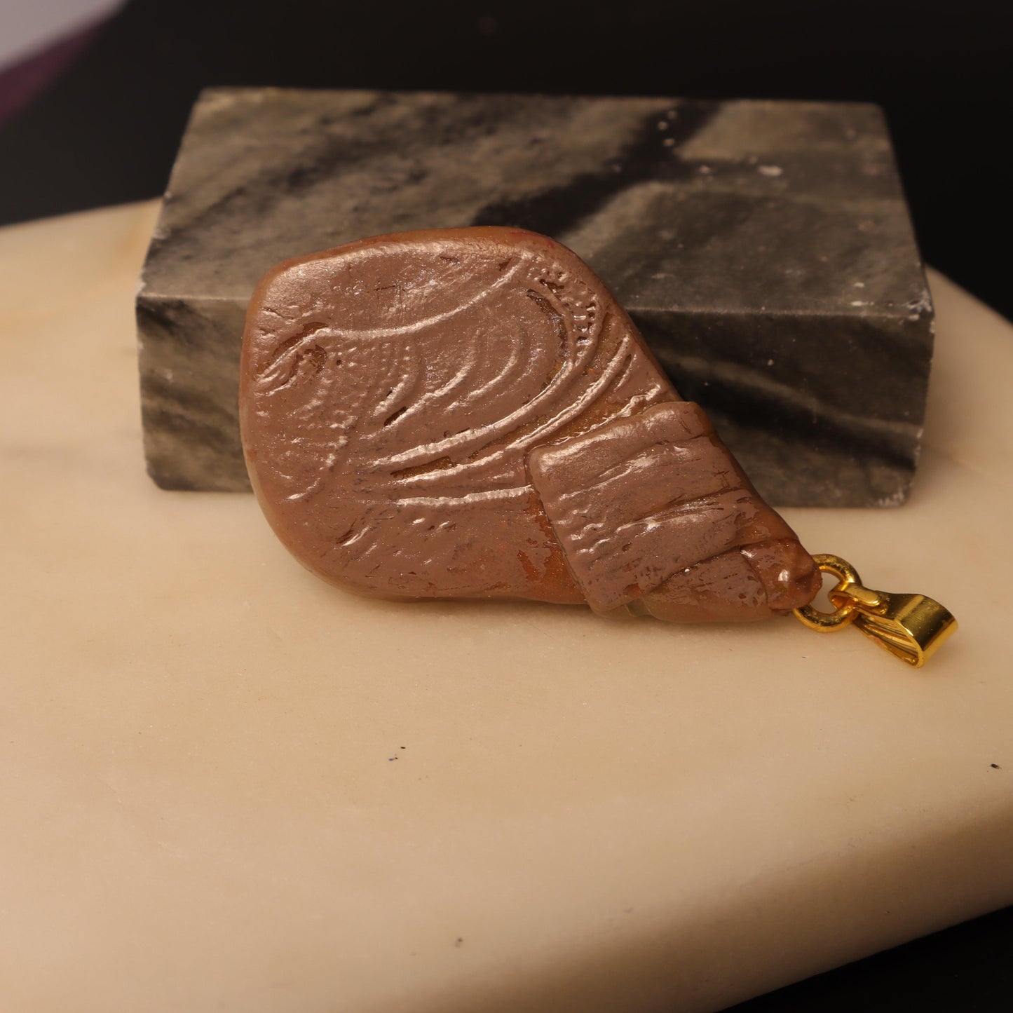 Handcrafted clay pendant with a polished stone, wrapped in earthy tones and finished with a gold-tone bail