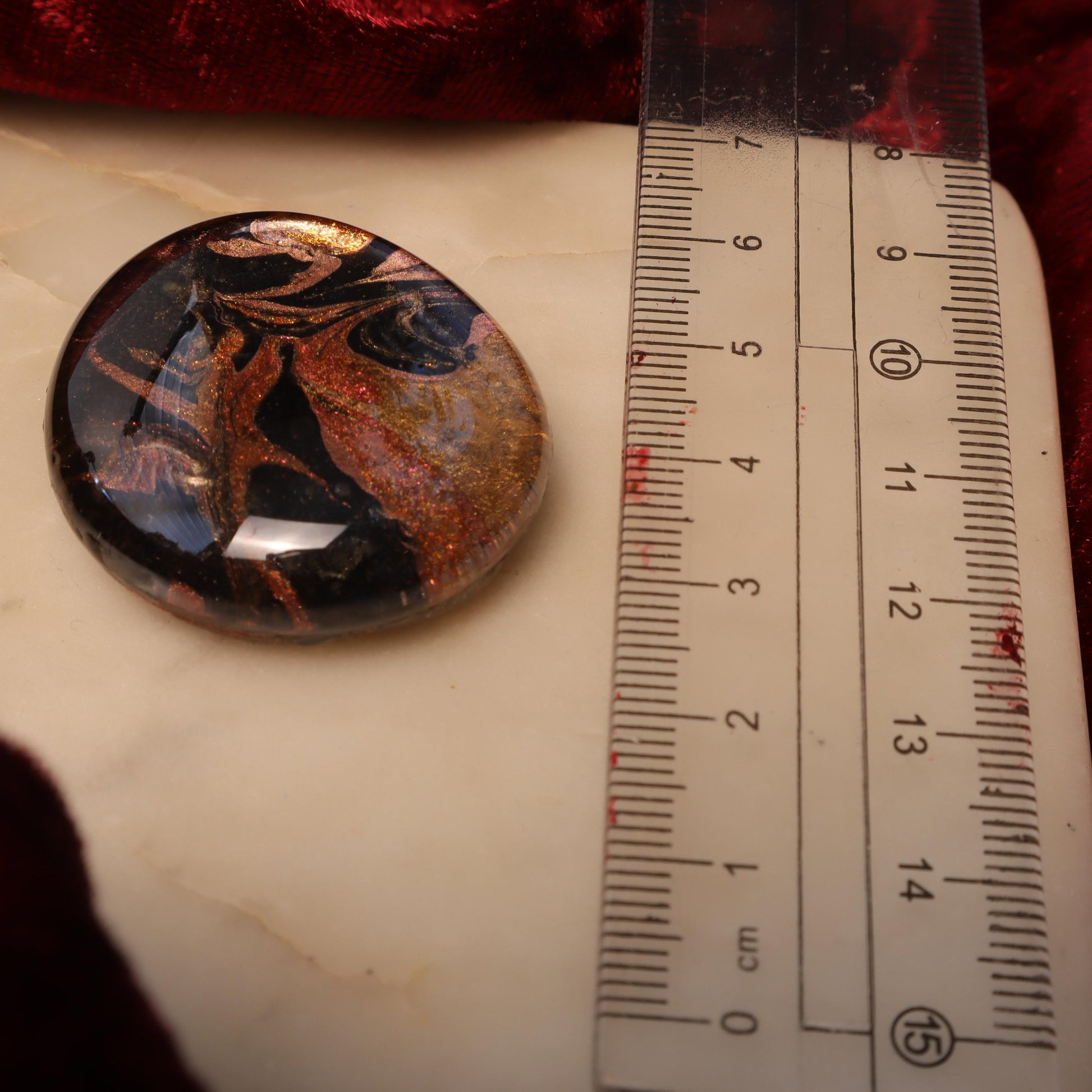 Handcrafted glass and resin worry stone featuring swirling black, gold, and copper tones with a smooth, polished finish