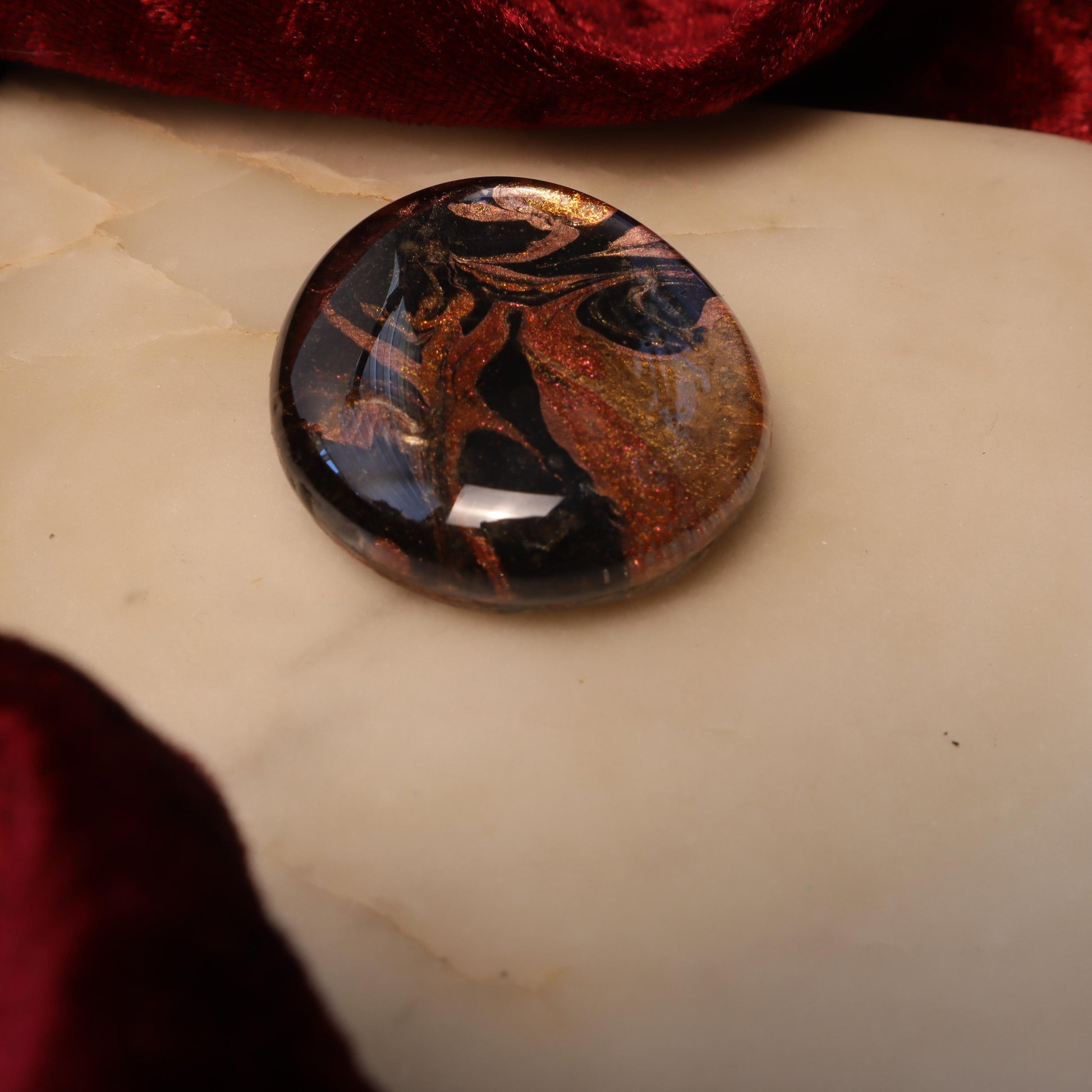 Handcrafted glass and resin worry stone featuring swirling black, gold, and copper tones with a smooth, polished finish