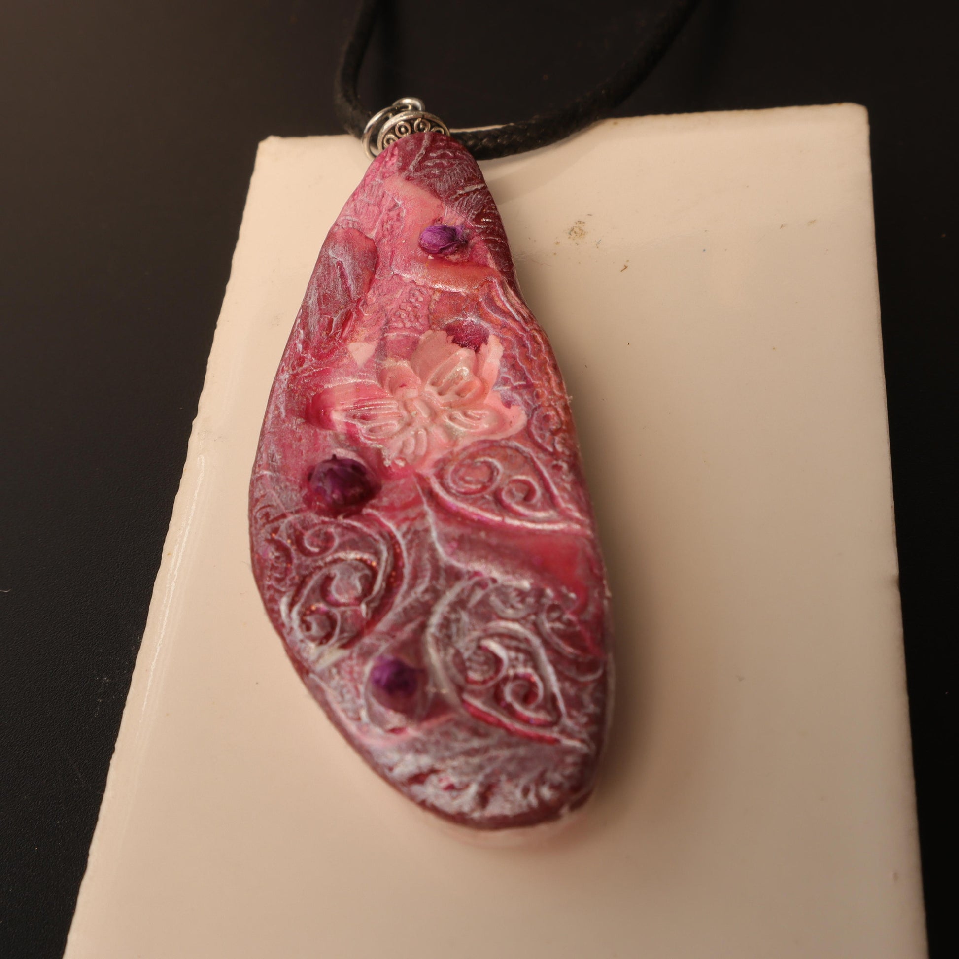 Handcrafted polymer clay pendant in rose and purple tones, embossed with intricate floral designs and silver-tone bail