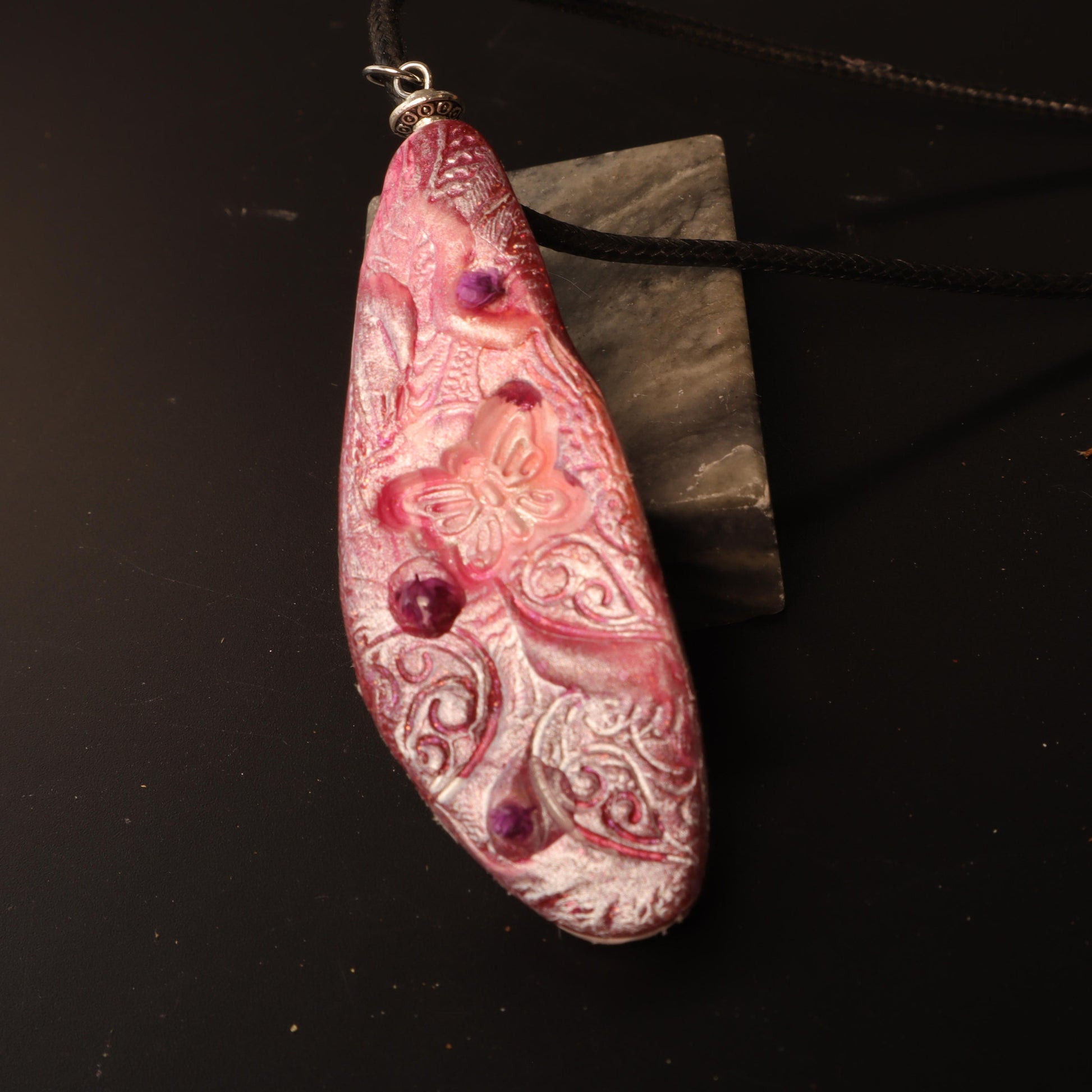 Handcrafted polymer clay pendant in rose and purple tones, embossed with intricate floral designs and silver-tone bail