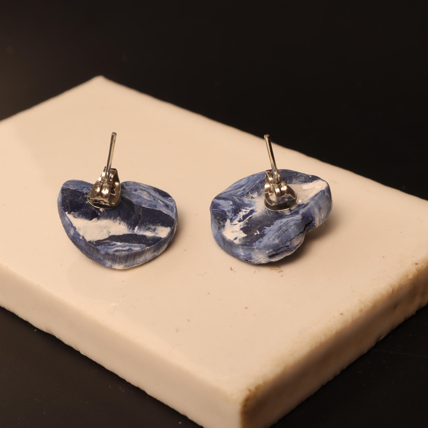 Heart-shaped polymer clay earrings in swirling blue and white patterns with silver flower accents