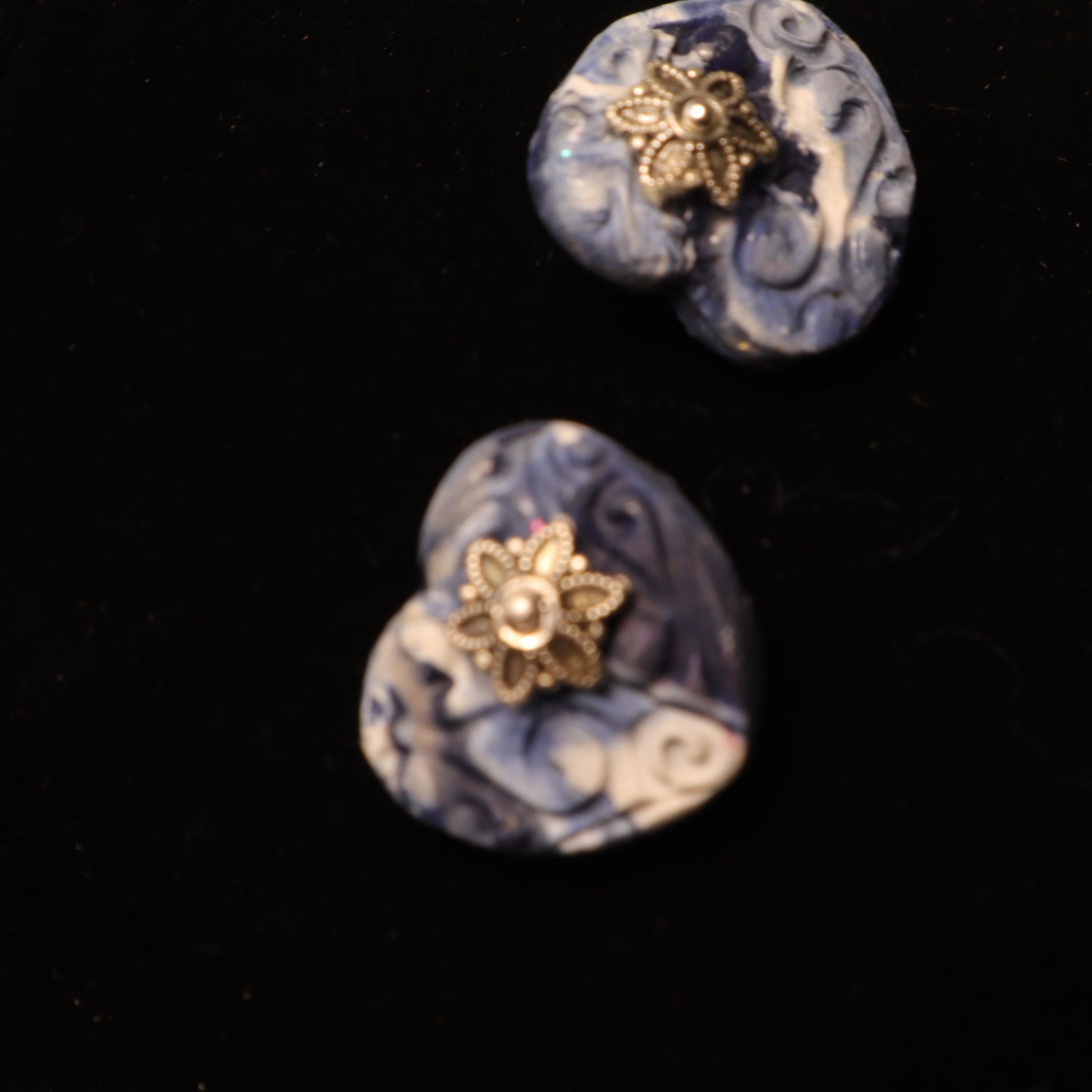 Heart-shaped polymer clay earrings in swirling blue and white patterns with silver flower accents