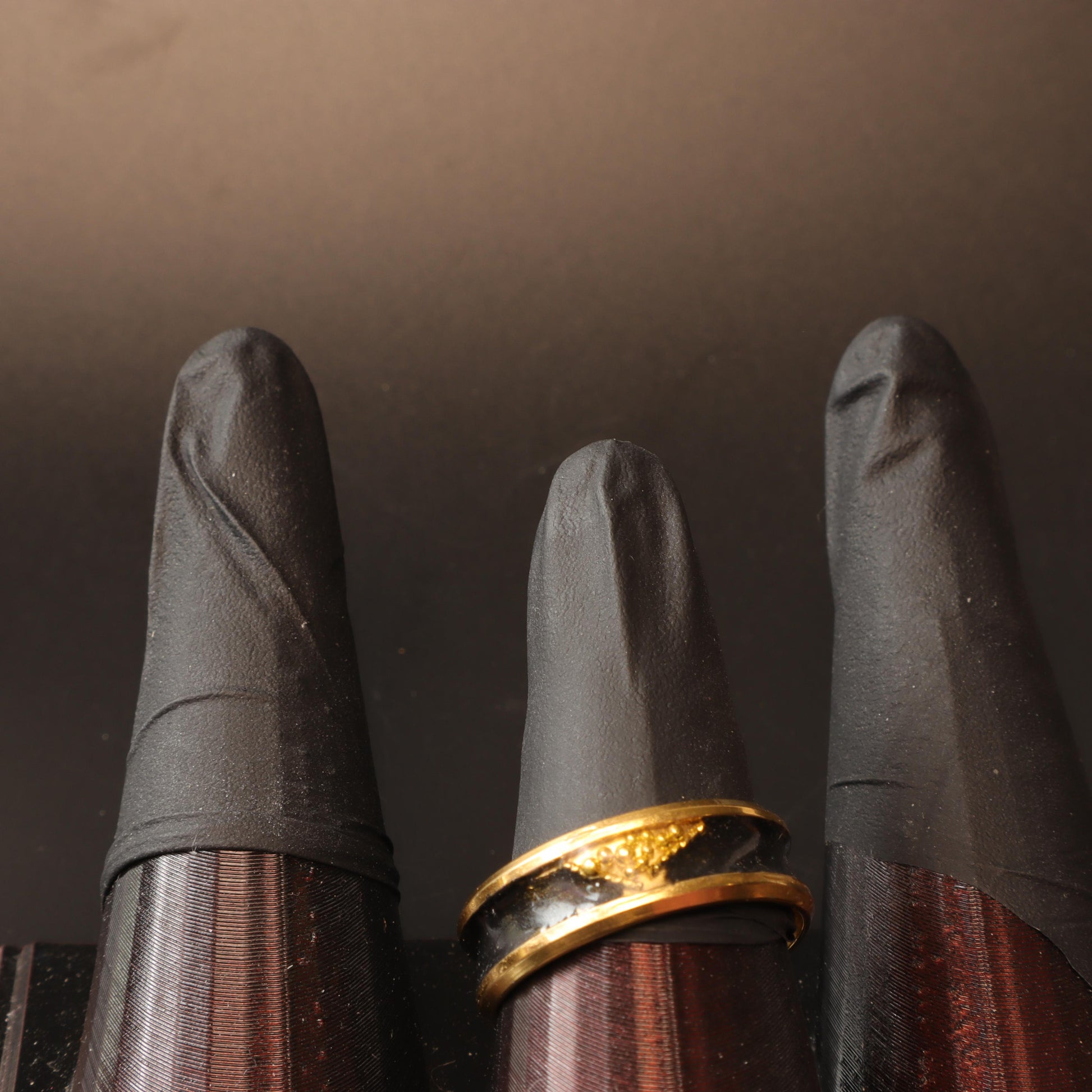 Handcrafted black resin ring with gold-tone bands displayed on a black stand, showcasing its sleek and luxurious design