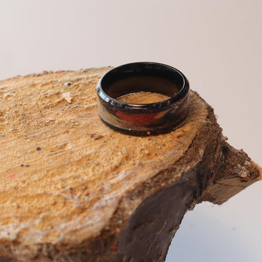 Black steel ring with polymer clay inlay on a rustic wooden surface